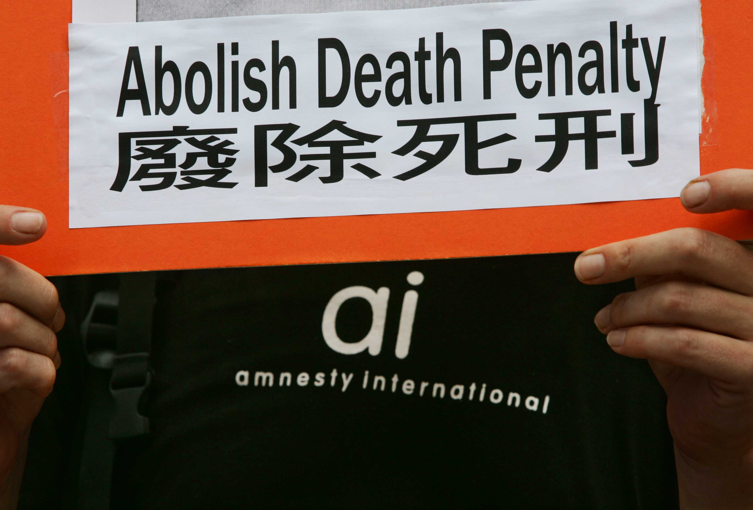 A protester from human rights group Amnesty International, carrying a placard demanding the abolition of death penalty in mainland China, demonstrate outside a Chinese liaison office in Hong Kong July 14, 2005. Amnesty International estimates that China executed at least 3,400 people in 2004. 