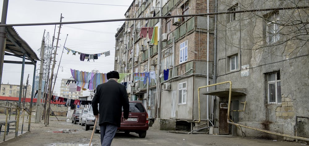 An older man walks across the courtyard of a dormitory for displaced persons in Baku, Azerbaijan