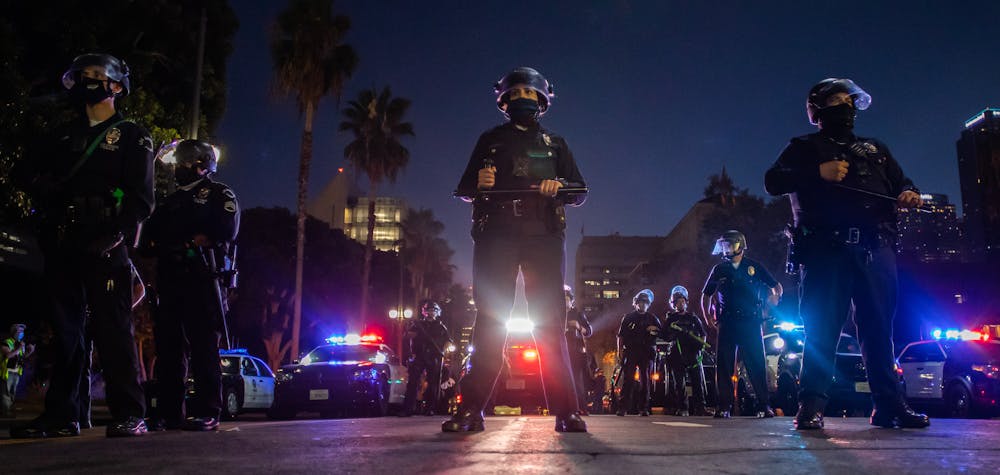 Police officers hold a line in front of LA City Hall during a protest demanding justice for George Floyd, Breonna Taylor and also in solidarity with Portland's protests, in Downtown Los Angeles, California, on July 25, 2020. (Photo by Apu GOMES / AFP)