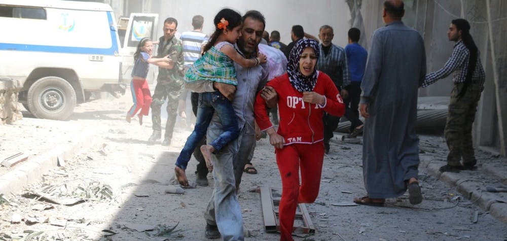 Une famille syrienne court pour se mettre à l'abri parmi les immeubles ruinés après un bombardement à Alep. 29/04/2016