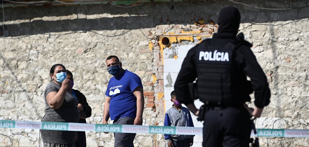 People wearing protective face masks are pictured as a police officer looks on while the coronavirus disease (COVID-19) spreads in the area around Roma settlements, in Zehra, Slovakia April 9, 2020. 