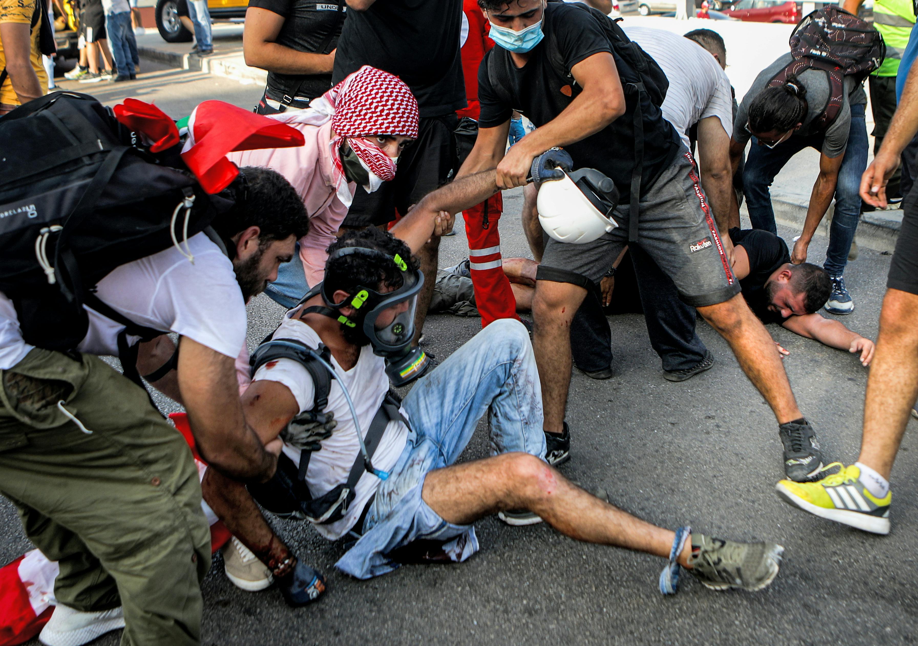 Lebanese protesters help a wounded demonstrator during clashes in downtown Beirut on August 8, 2020, following a demonstration against a political leadership they blame for a monster explosion that killed more than 150 people and disfigured the capital Beirut. 
