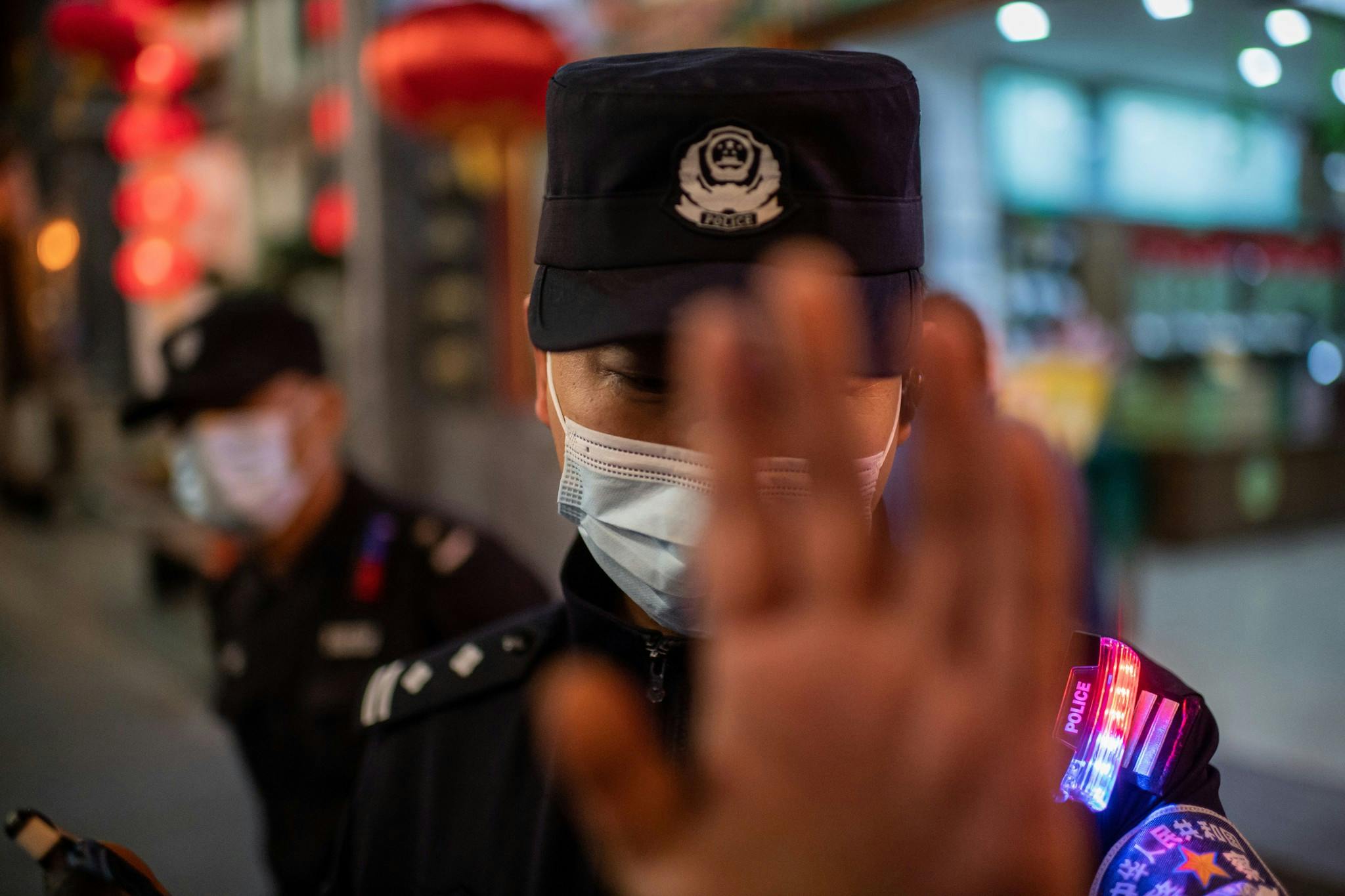 Un agent de police portant un masque facial par mesure de prévention contre le Covid-19 (nouveau coronavirus) tente d'empêcher un photojournaliste de prendre des photos dans une rue à l'extérieur d'un complexe commercial à Pékin, le 13 octobre 2020.