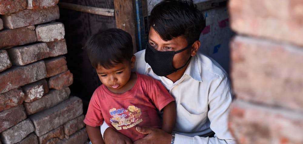 Un réfugié rohingya portant un masque protecteur se trouve à l'extérieur de son domicile temporaire alors que de la nourriture gratuite est distribuée par People for Social Development en collaboration avec la police de Delhi, le 15e jour de l'emprisonnement national de 21 jours pour freiner la propagation du coronavirus, à Okhla en avril. 8, 2020 à New Delhi, Inde. 