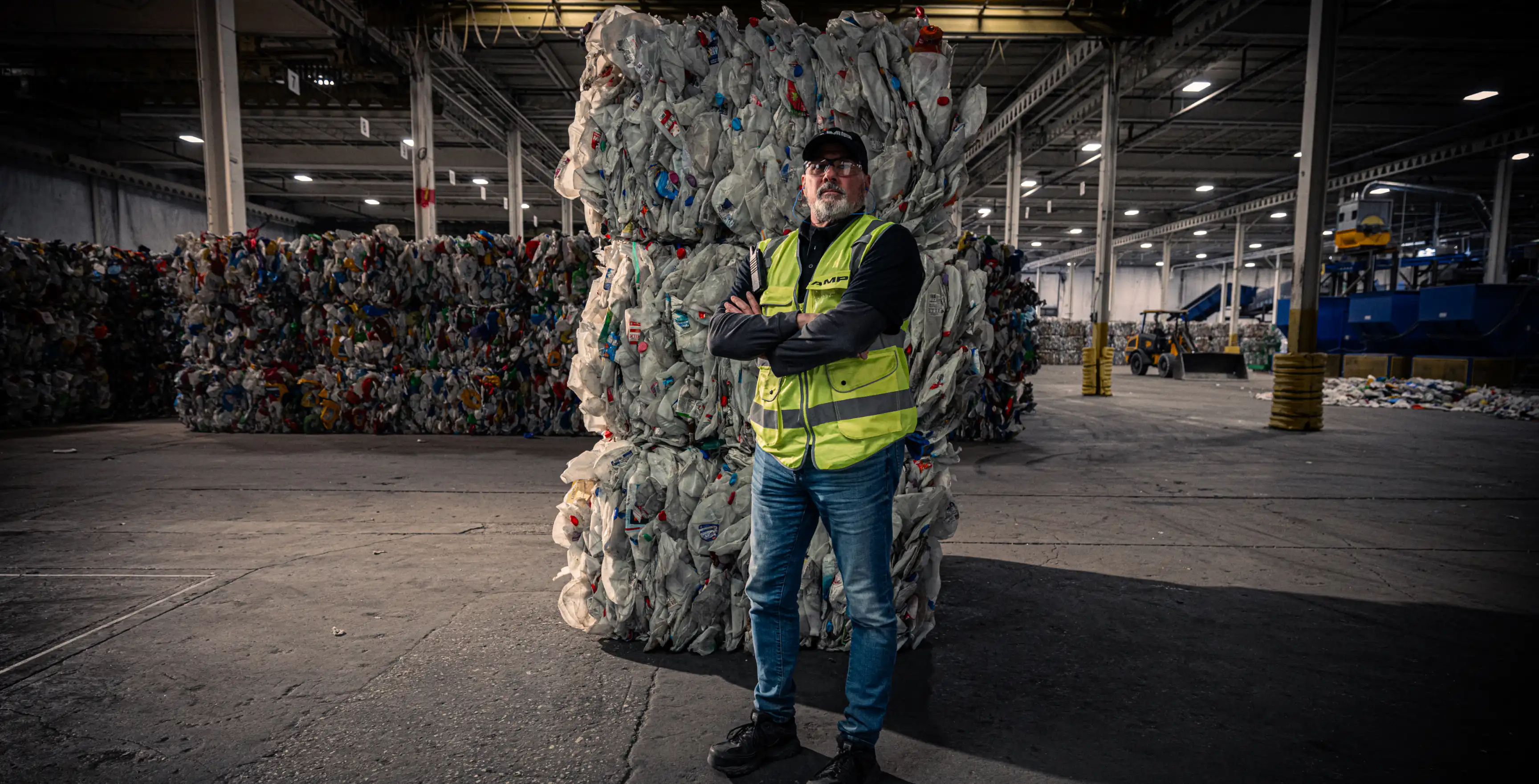 Factory worker in front of a stack of trash that has been sorted by AMP Sortation technologies