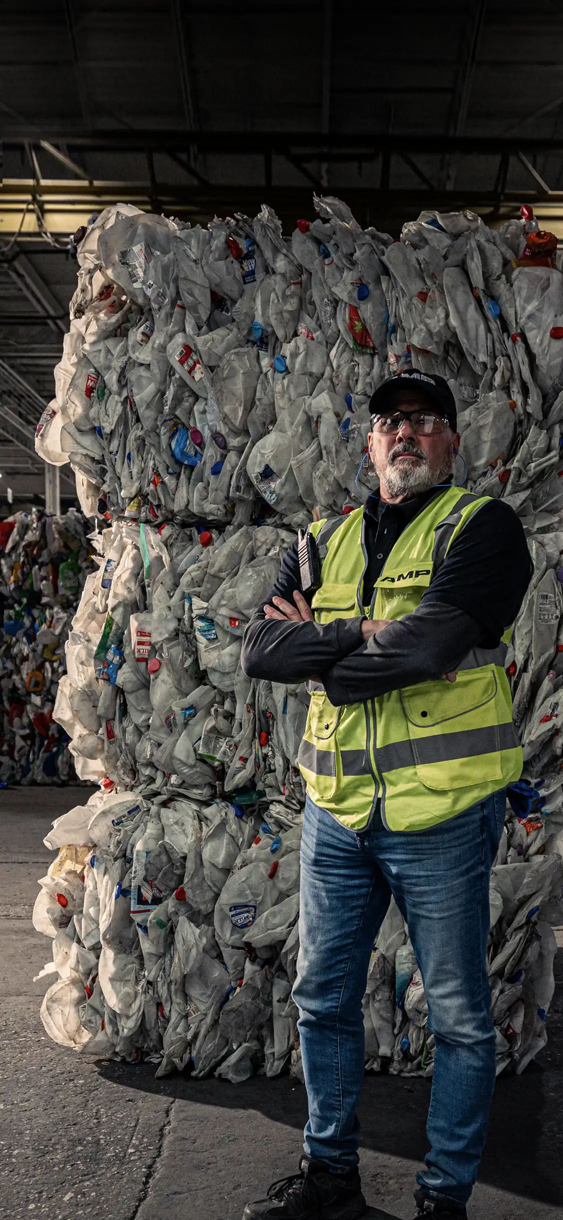 Factory worker in front of a stack of trash that has been sorted by AMP Sortation technologies