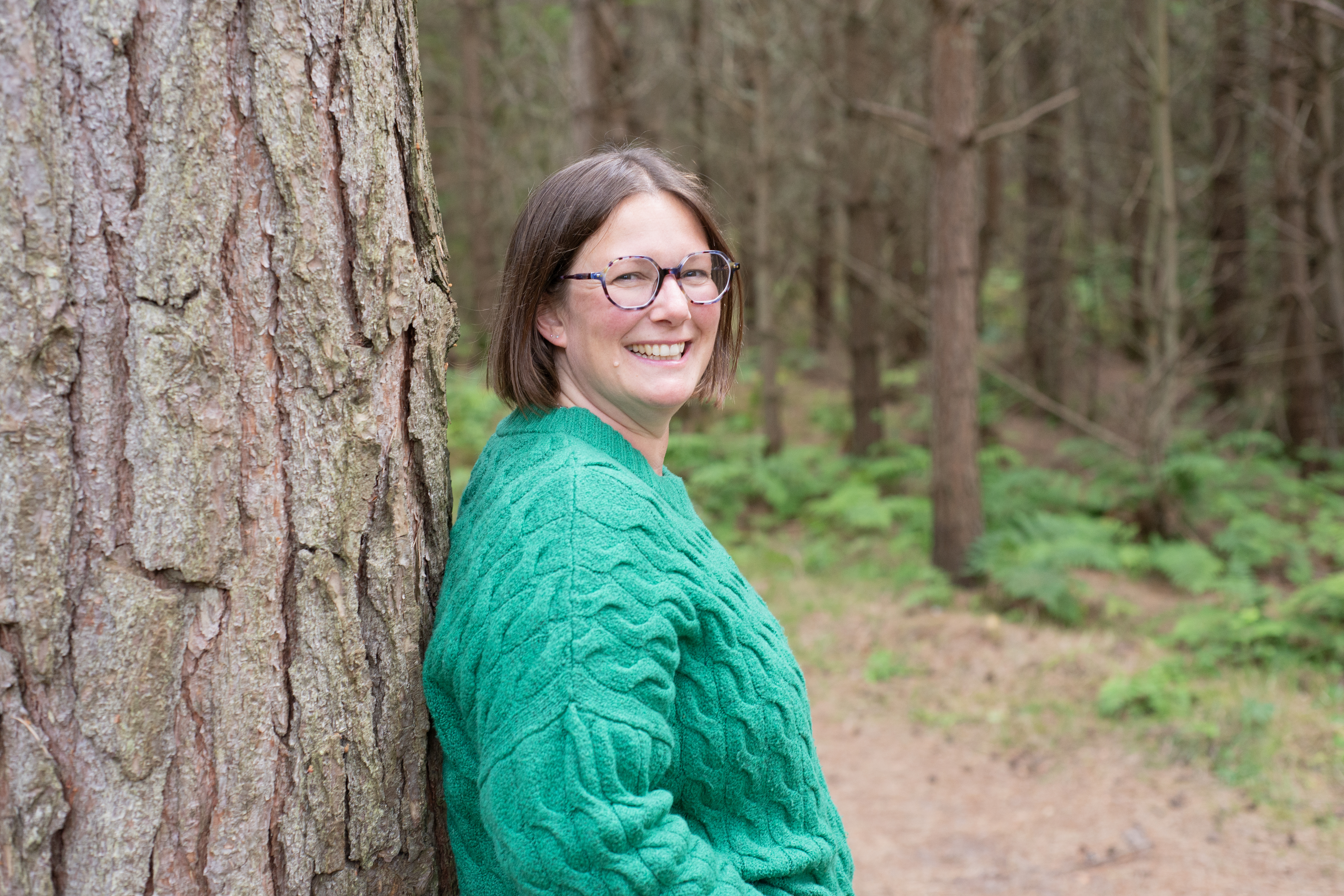 Amy standing leaning against tree