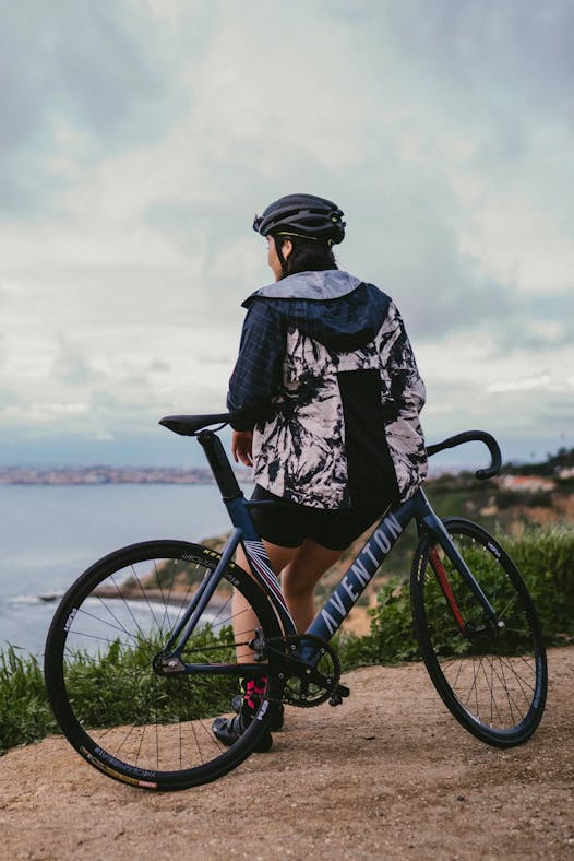 Image of a woman leaning against an Aventon bike looking out a coastline 