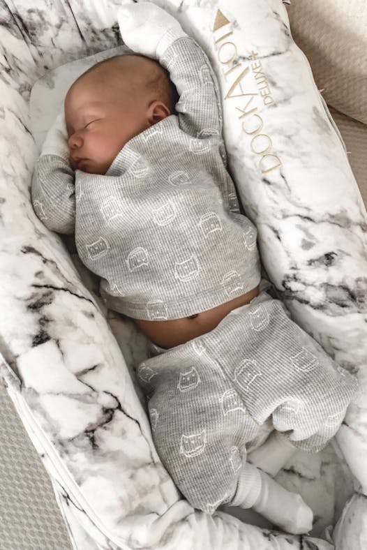 A top-down picture of a baby sleeping peacefully in a pillow bed