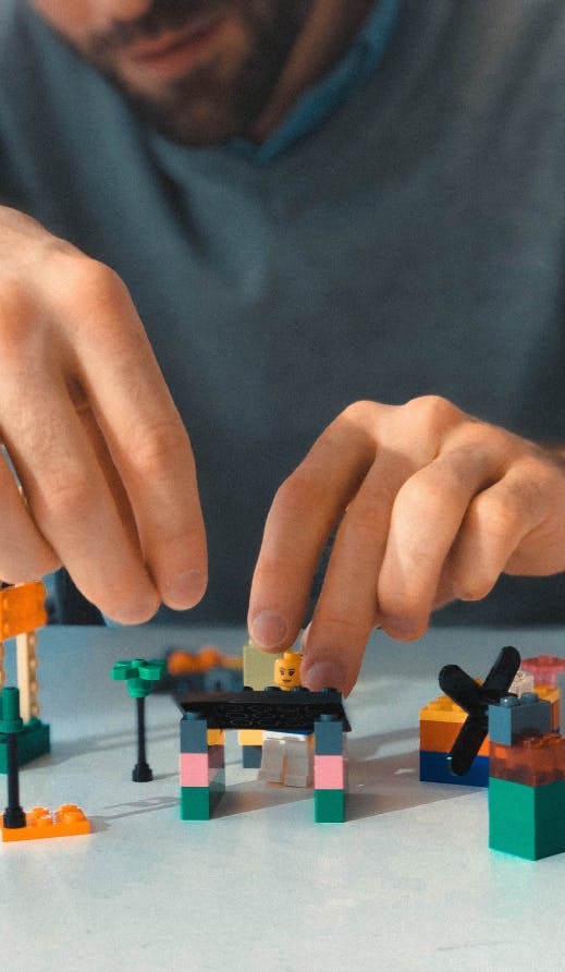 A photo of a user experience researcher ideating UX solutions by building with Legos at a table.
