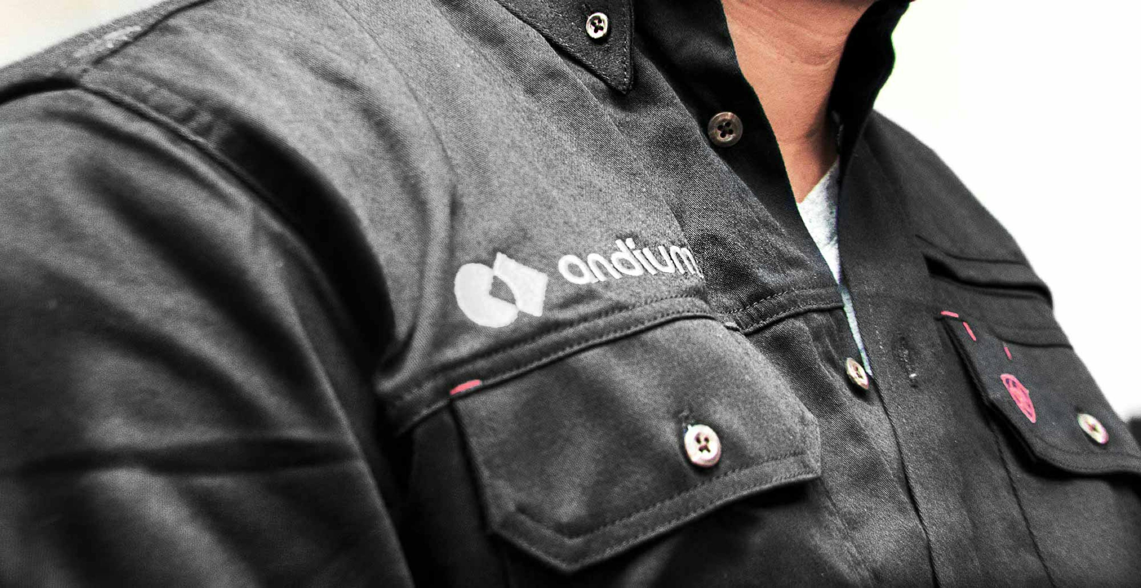 Close-up of a person wearing a black shirt with the Andium logo on the chest pocket, representing a member of the Andium team.