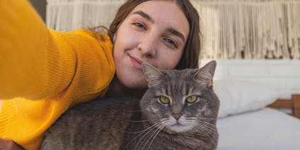 Donna che si scatta un selfie con il suo gatto sul letto
