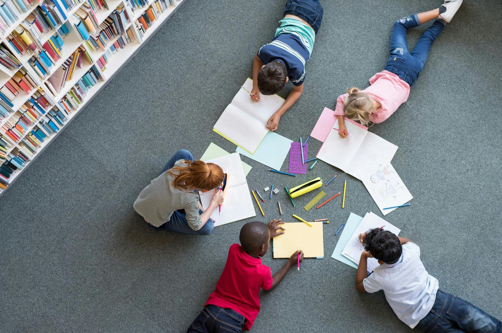 Children writing in books on the floor