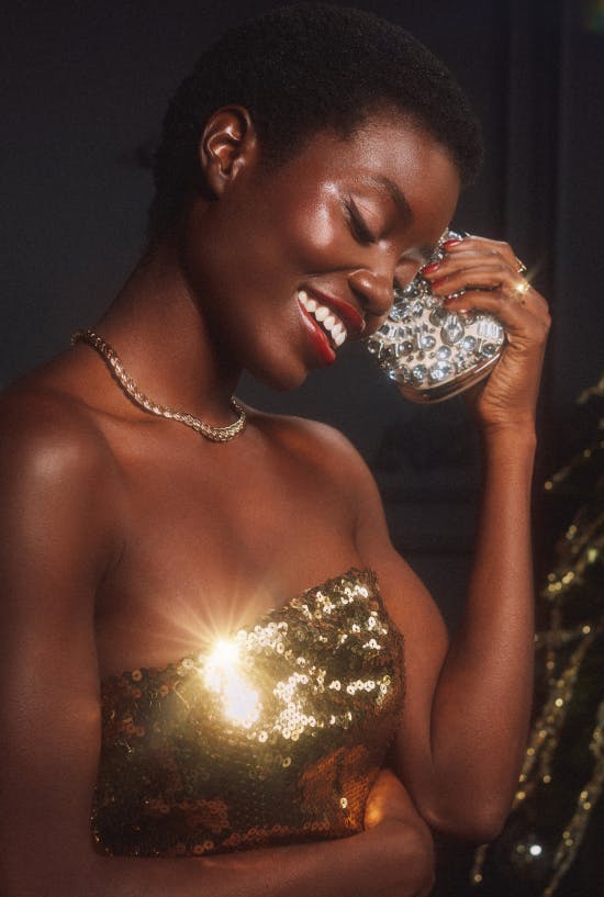 A woman smiles, wearing a gold dress