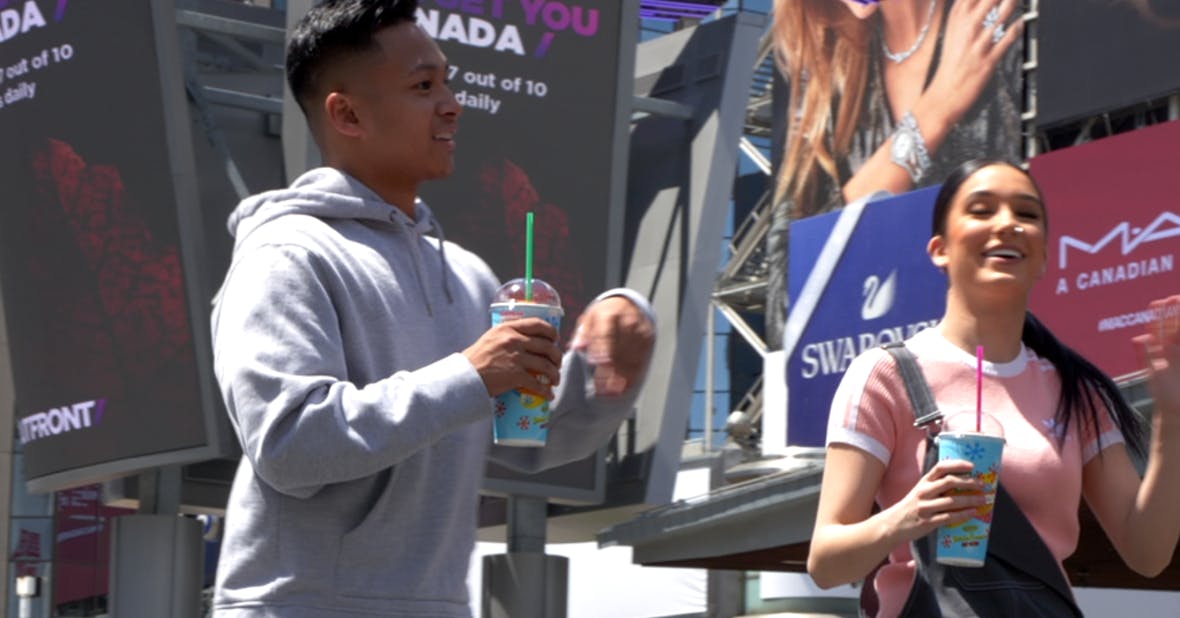 A man and woman smiling while holding slurpees