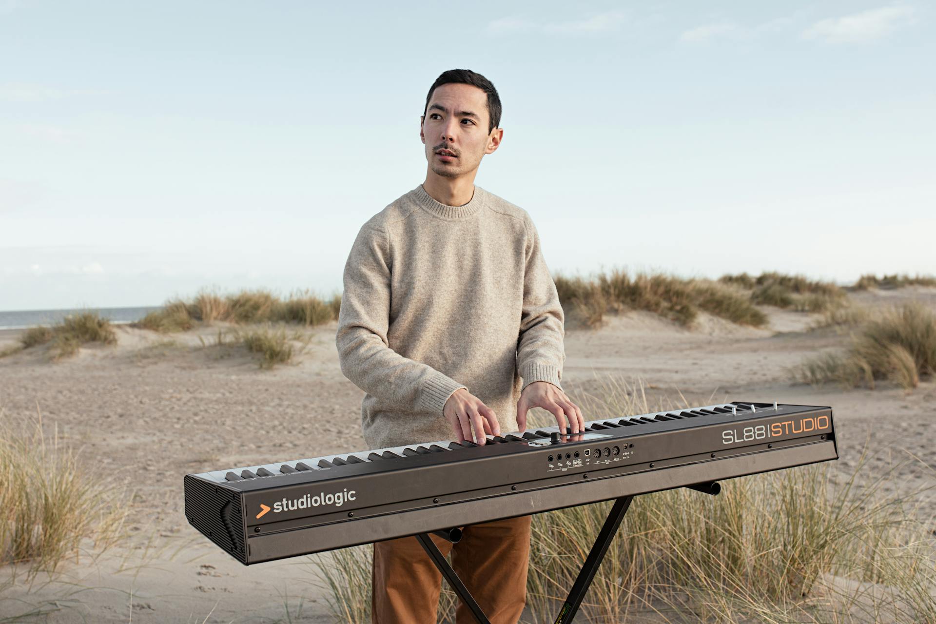 Photo d'Antoine Sugita avec son piano sur une plage