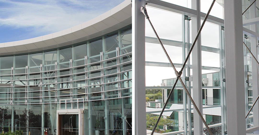 Glass fa&ccedil;ade supported by a structural tension rod system with steel frames, enhancing stability while maintaining a modern, transparent architectural design.