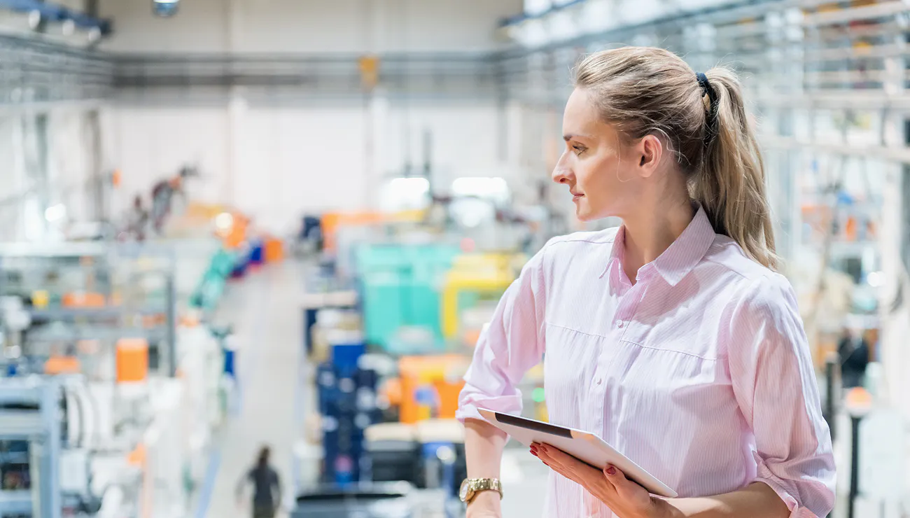 Woman with tablet overlooking industrial setting