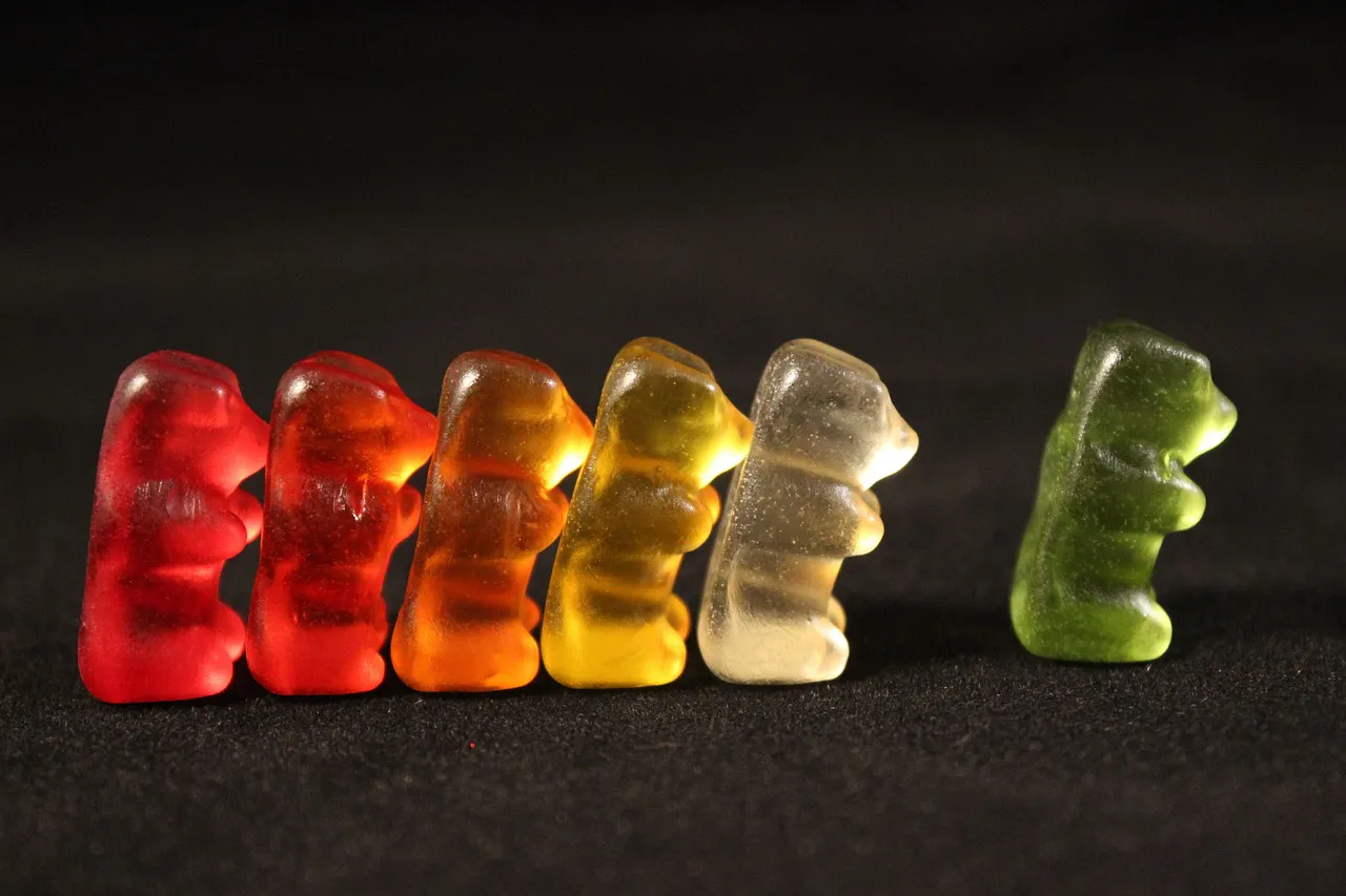 Gummy bears lined up by color facing the same direction, with the green gummy in front to symbolize the variety of cannabis laws by state
