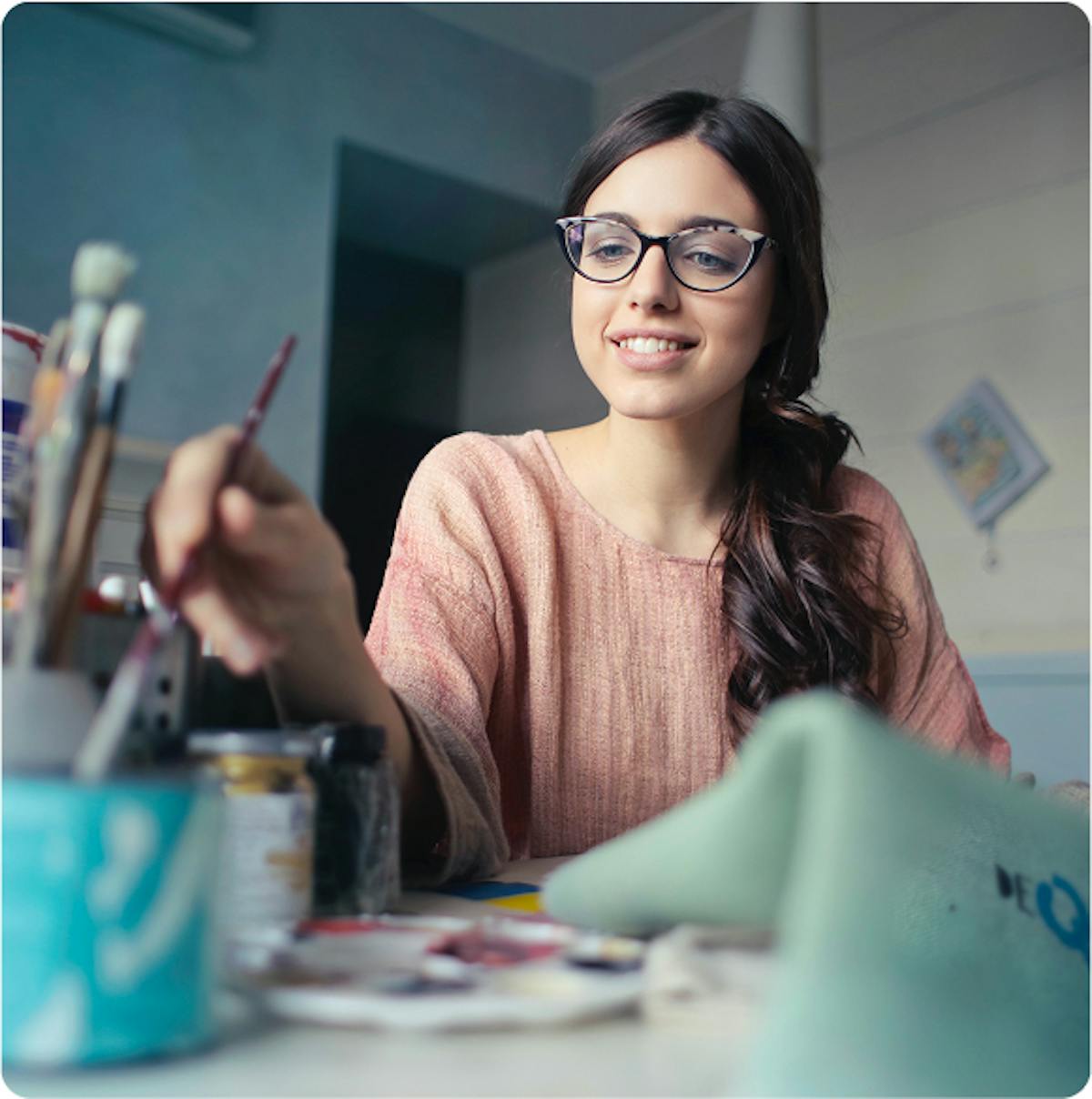 Mulher pintando um desenho, feliz, com óculos e cabelos longos