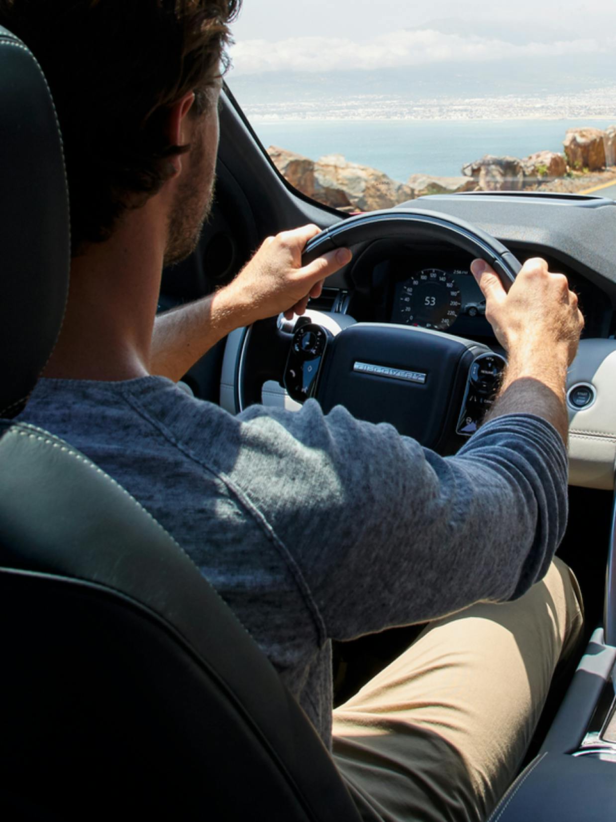 FINN – Branding "A Sustainable Car Subscription Service": Photo showing a man driving a car with a scenic coastal view by HY.AM