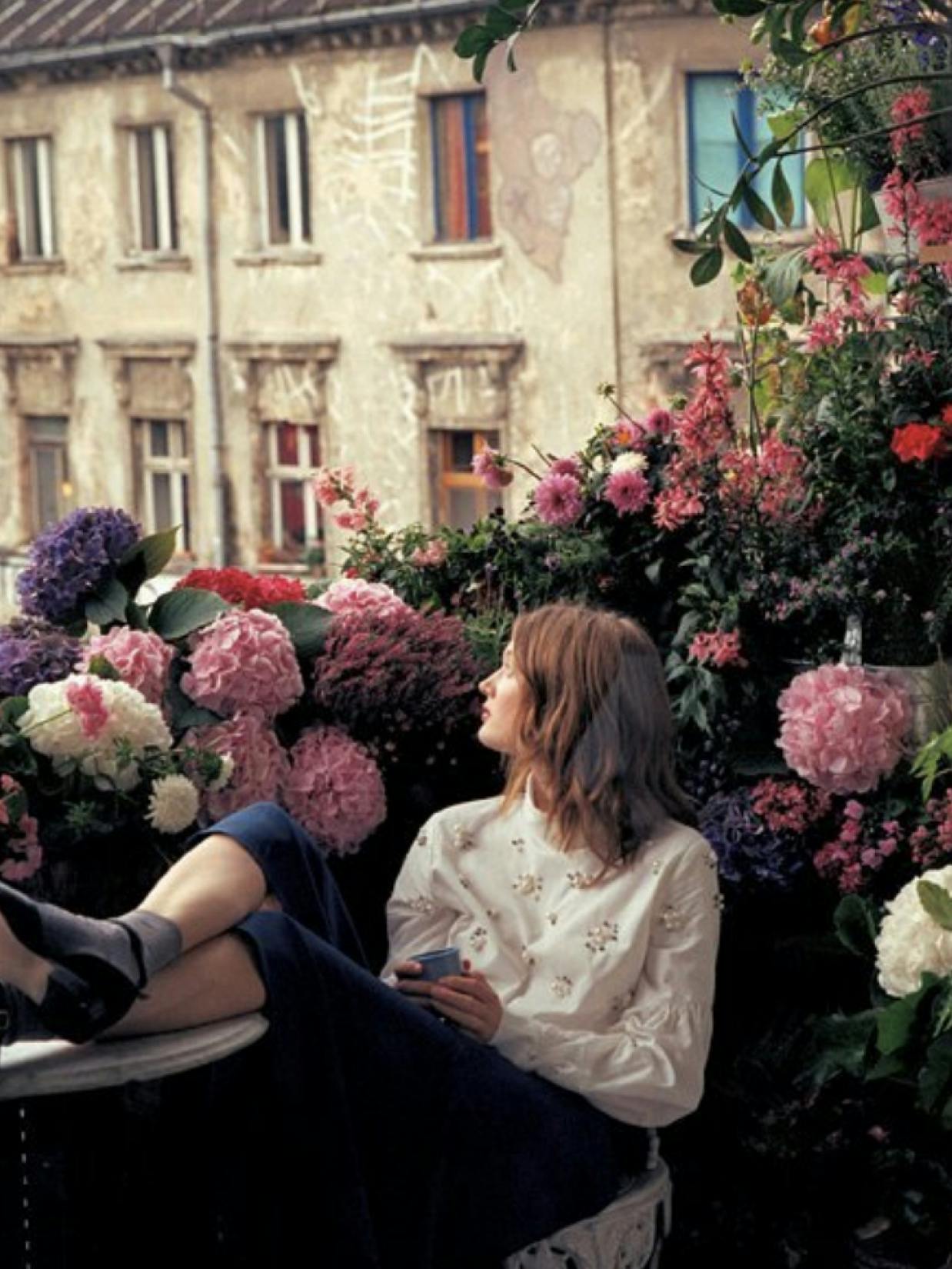 mint & berry by Zalando – Brand Campaign "The world needs more romance": Photo showing a woman sitting amongst flowers on a balcony, looking away from the camera x HY.AM Studios