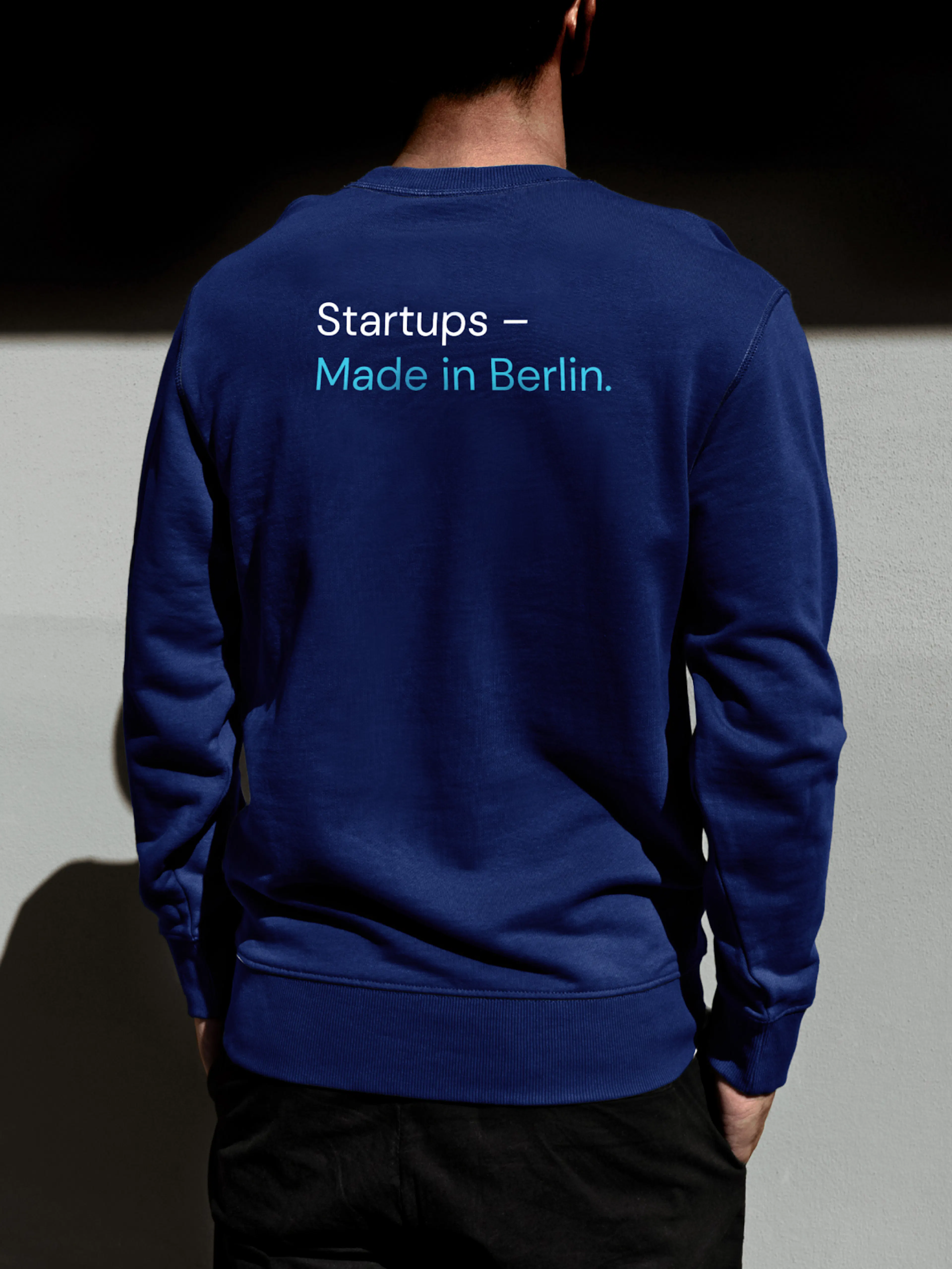 IBB Ventures – Brand Design, E-Commerce, Experience Design "Investing in Berlin’s future": Mockup showing the back of a person wearing a navy blue sweatshirt with "Startups – Made in Berlin." printed on it x HY.AM Studios
