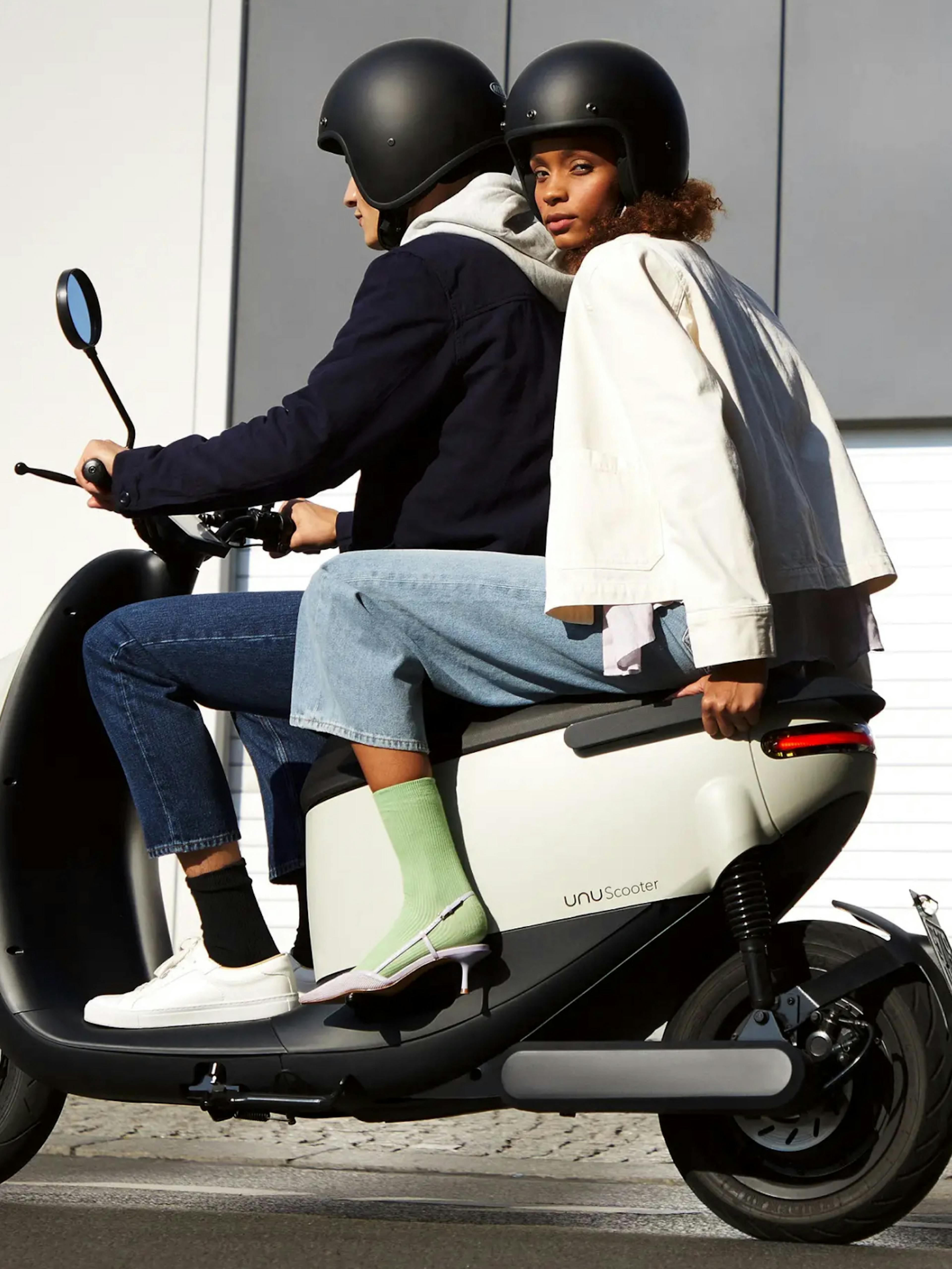 unu – Brand Design, E-Commerce, Experience Design "Discovering your city with unu": Photo showing two people wearing helmets riding a white unu Scooter x HY.AM Studios