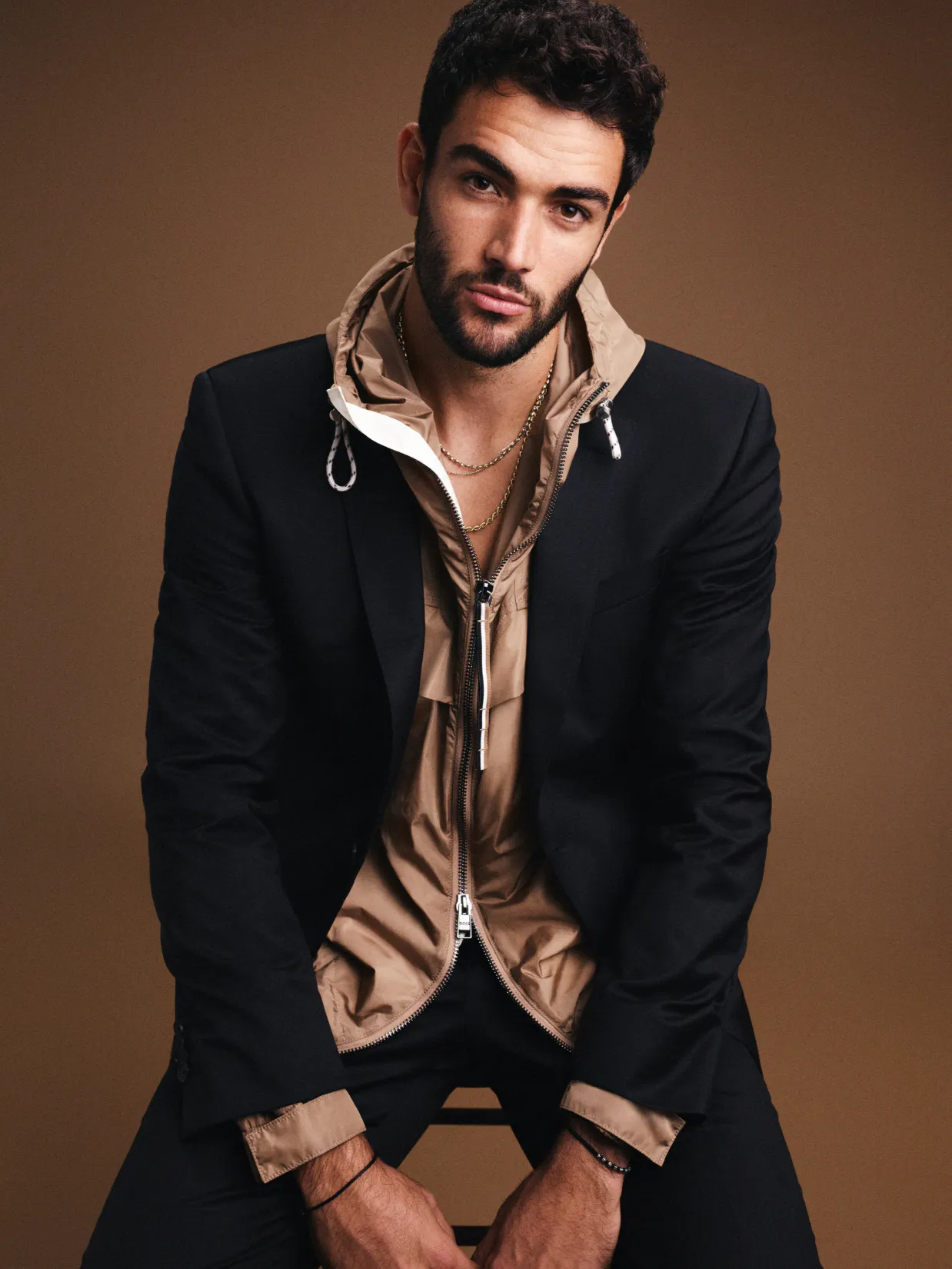 Hugo Boss – Brand Design "Bringing Hugo Boss to the streets": Photo showing a man wearing a black suit jacket over a tan hooded jacket and gold chains x HY.AM Studios