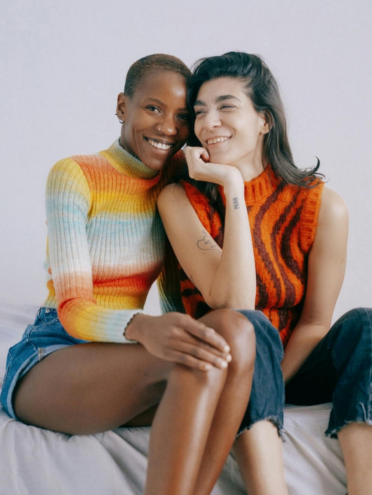Bumble – Strategy & Brand Activation "Making the first move": Photo showing two smiling women sitting close together, one with a rainbow-striped sweater and the other with an orange tiger-striped sweater x HY.AM Studios