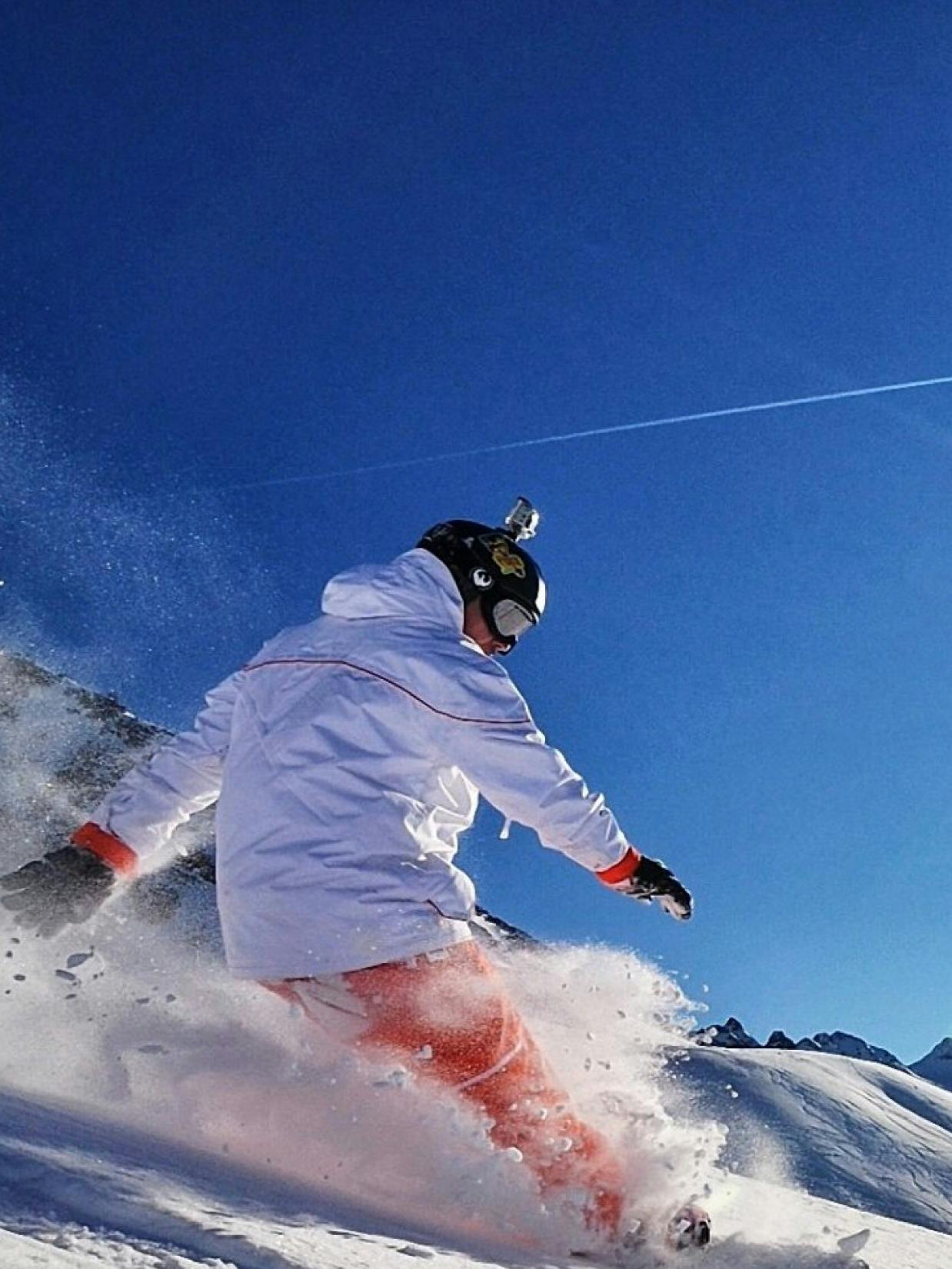 Grover – Brand Design, E-Commerce, Experience Design "Why buy when you can rent it": Photo showing a snowboarder in a white jacket and orange pants carving through snow, with a GoPro camera mounted on their helmet x HY.AM Studios