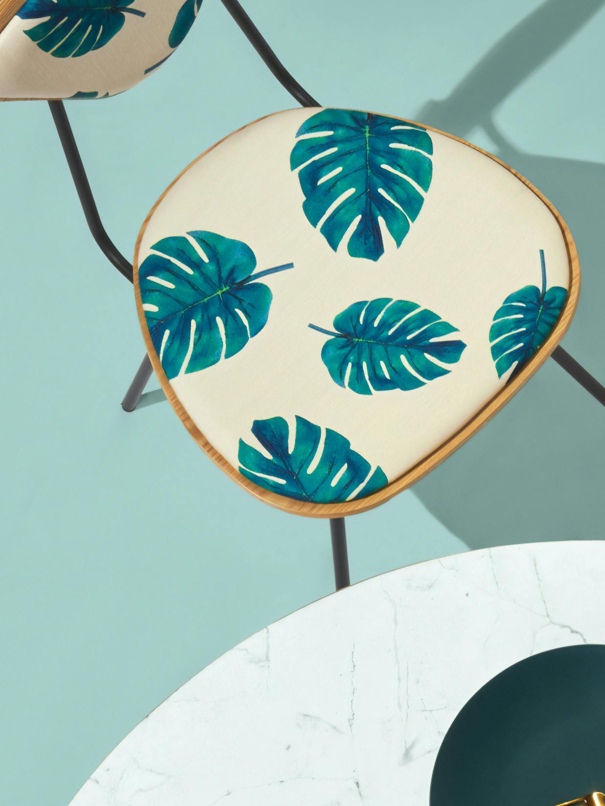 Home24 – Brand Design, E-Commerce, Experience Design "Europe's online store for furniture": Photo showing a chair with a cream-colored seat featuring a pattern of teal monstera leaves x HY.AM Studios