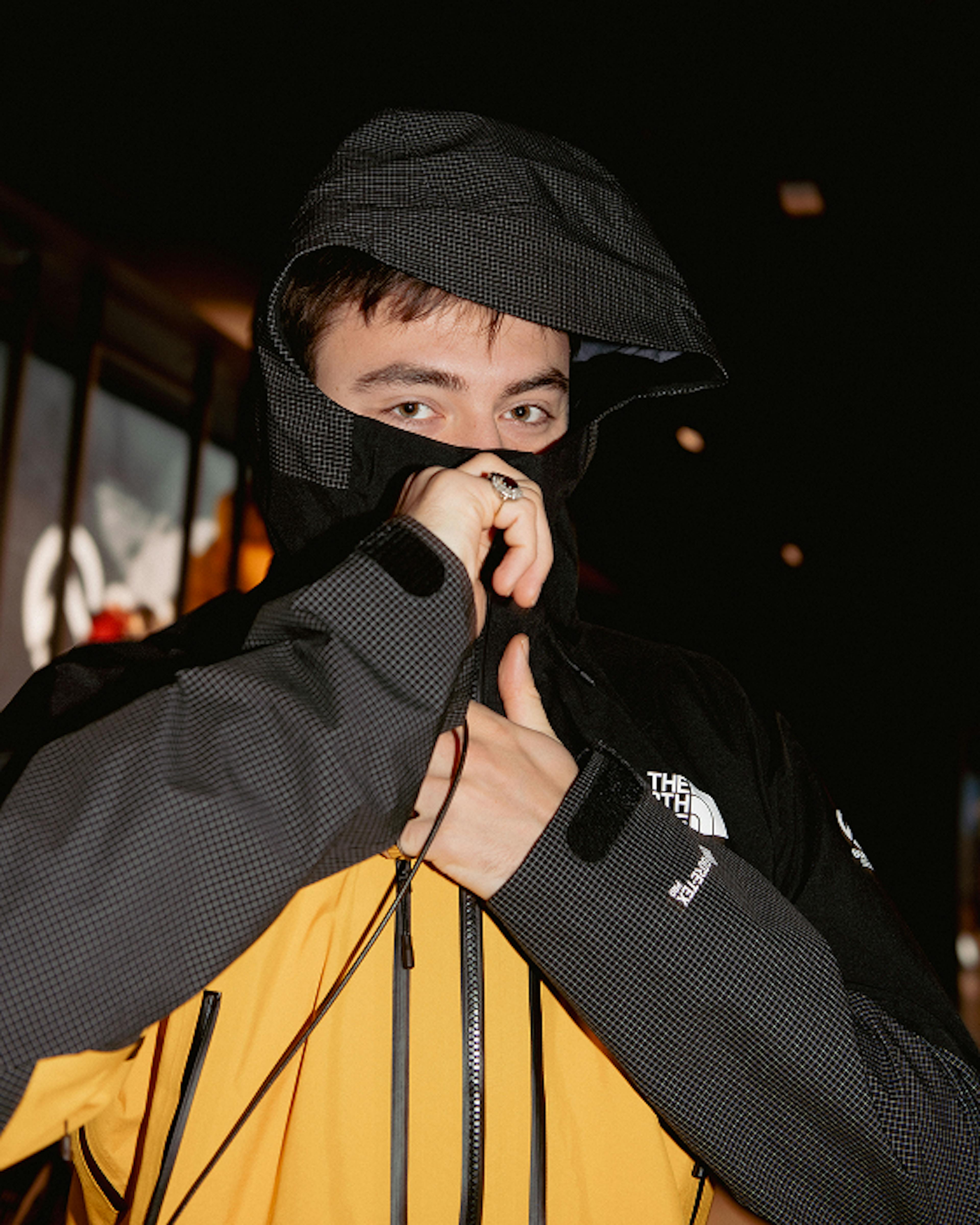 The North Face – Brand Activation "Summit Series Brand Activation": Photo showing a person wearing a yellow and black jacket, pulling up the hood and covering their mouth x HY.AM Studios