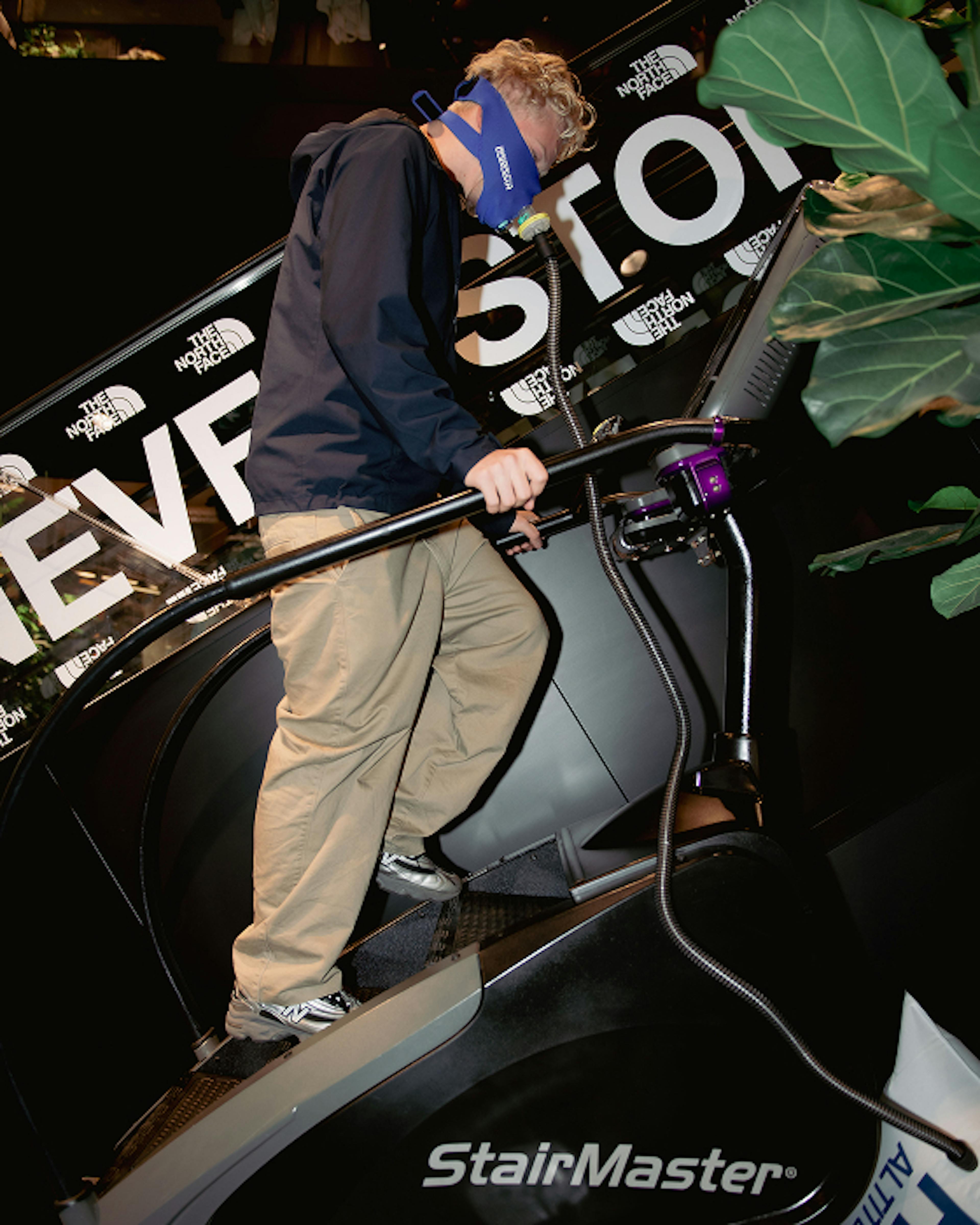 The North Face – Brand Activation "Summit Series Brand Activation": Photo showing a person wearing a blue mask and climbing a StairMaster with The North Face branding x HY.AM Studios