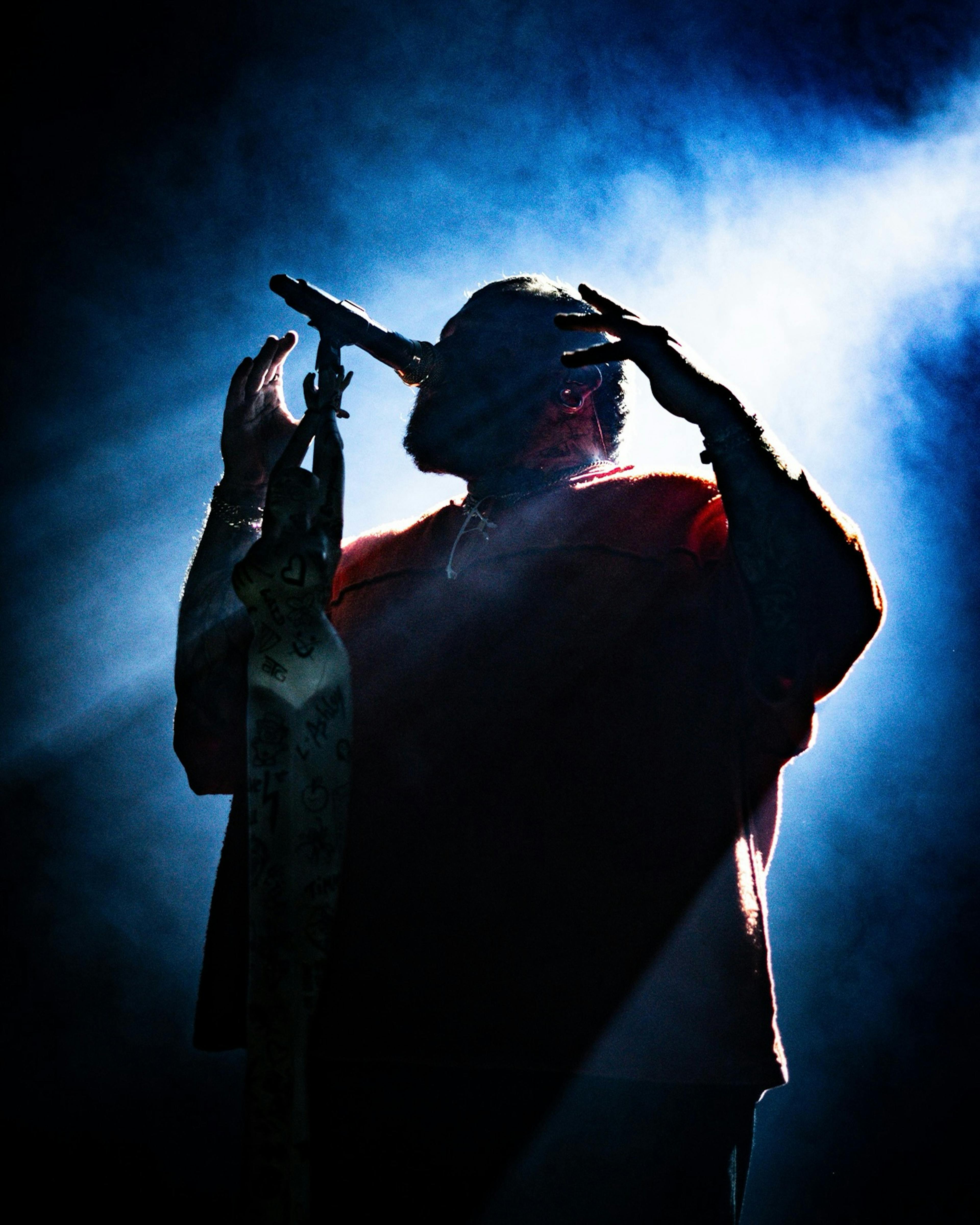 Warner Music – Brand Design "A Refined Brand System for Central Europe": Photo showing a silhouetted performer on stage with hands raised, illuminated by blue stage lights and smoke x HY.AM Studios