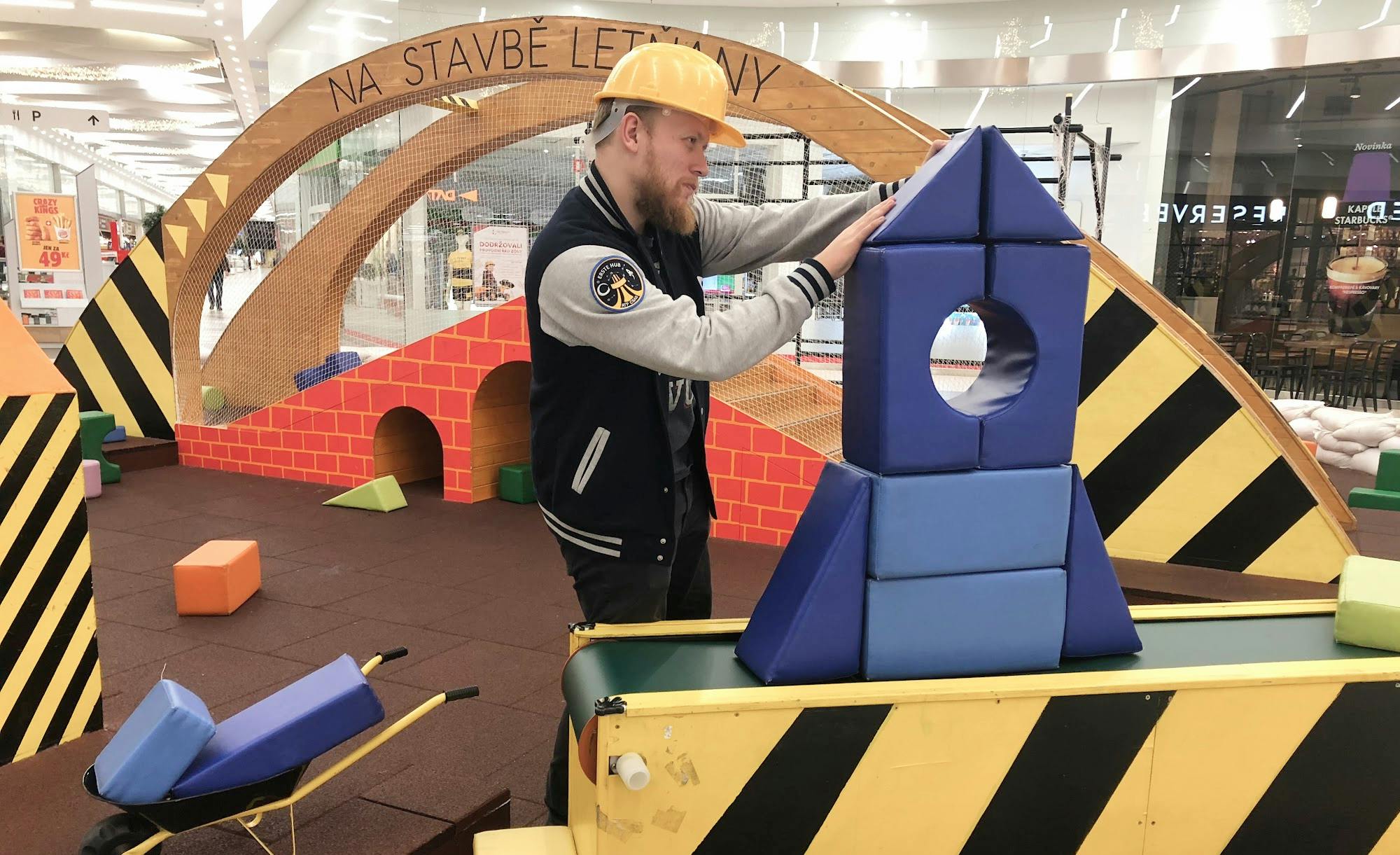 Co-founder Vratislav in a construction-themed play area building a structure with blue foam blocks.