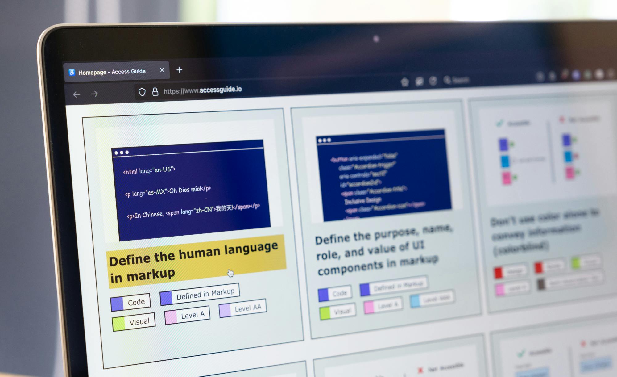 A close-up of a laptop screen displaying a webpage titled 'Access Guide,' featuring examples of HTML markup and guidance on defining human language in code.