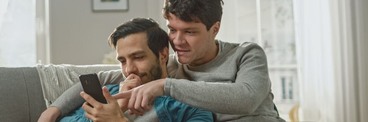 Gay couple checking their phones - IVF with donor eggs