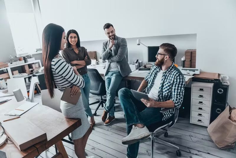 Image shows 4 people in a work environment showcasing how communication is important.