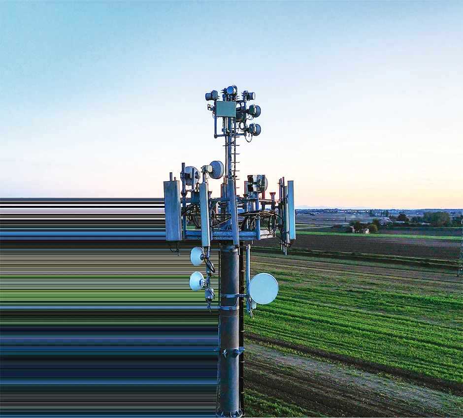 Telecommunications cell tower rising above farmland at sunset