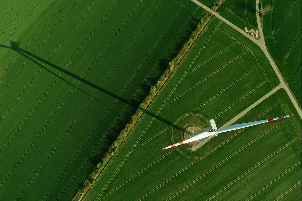 Aerial view of wind turbine in a green field with roads