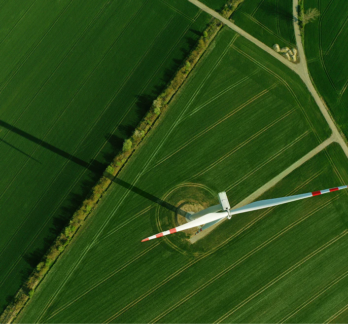 Aerial view of wind turbine in a green field with roads