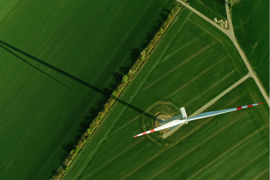 Aerial view of wind turbine in a green field with roads