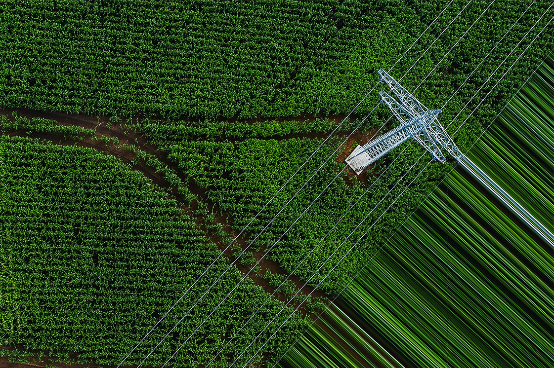 Aerial view of field with electricity pylon and power lines