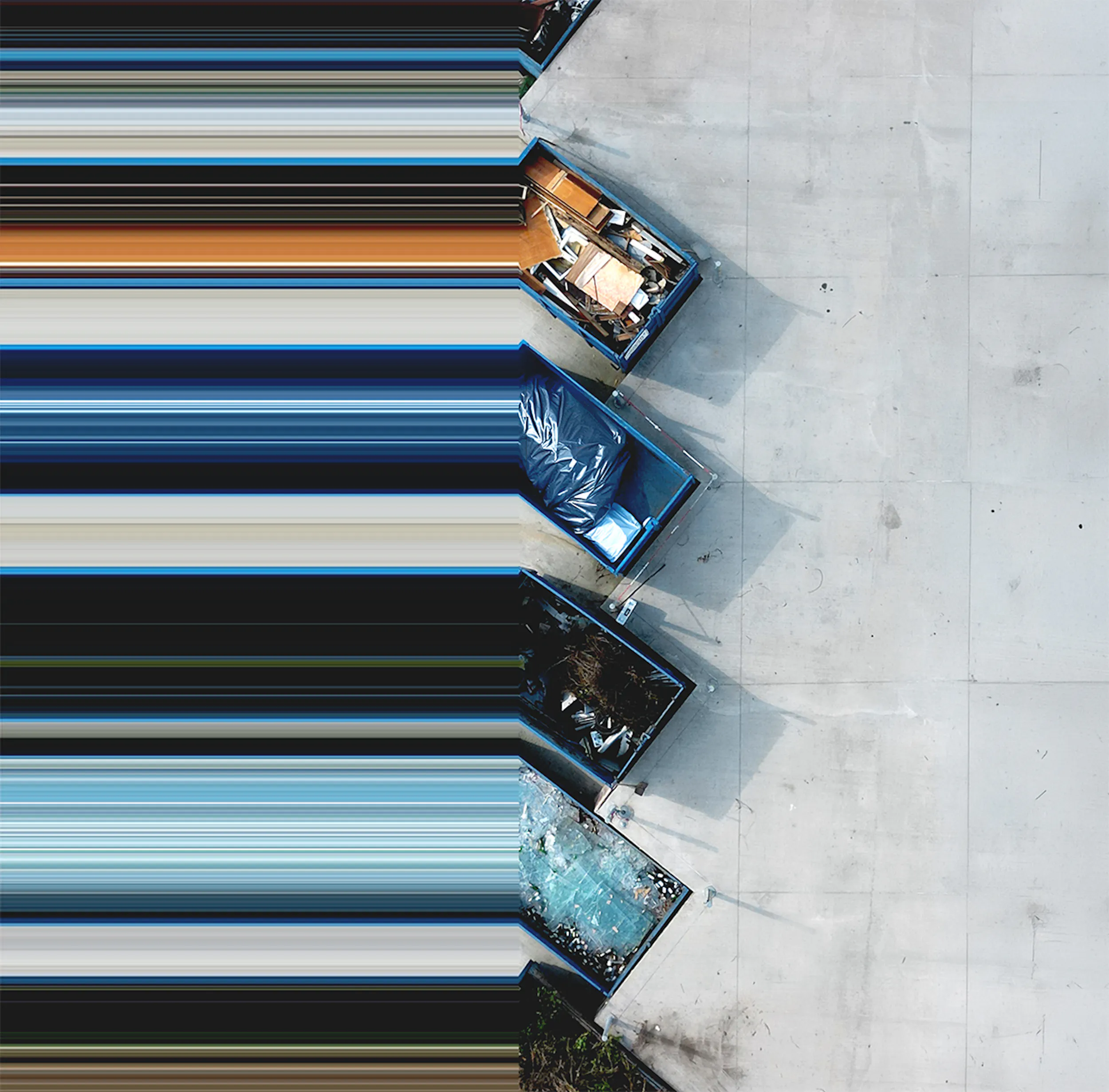 Aerial view of a row of large waste dumpsters lined up on pavement