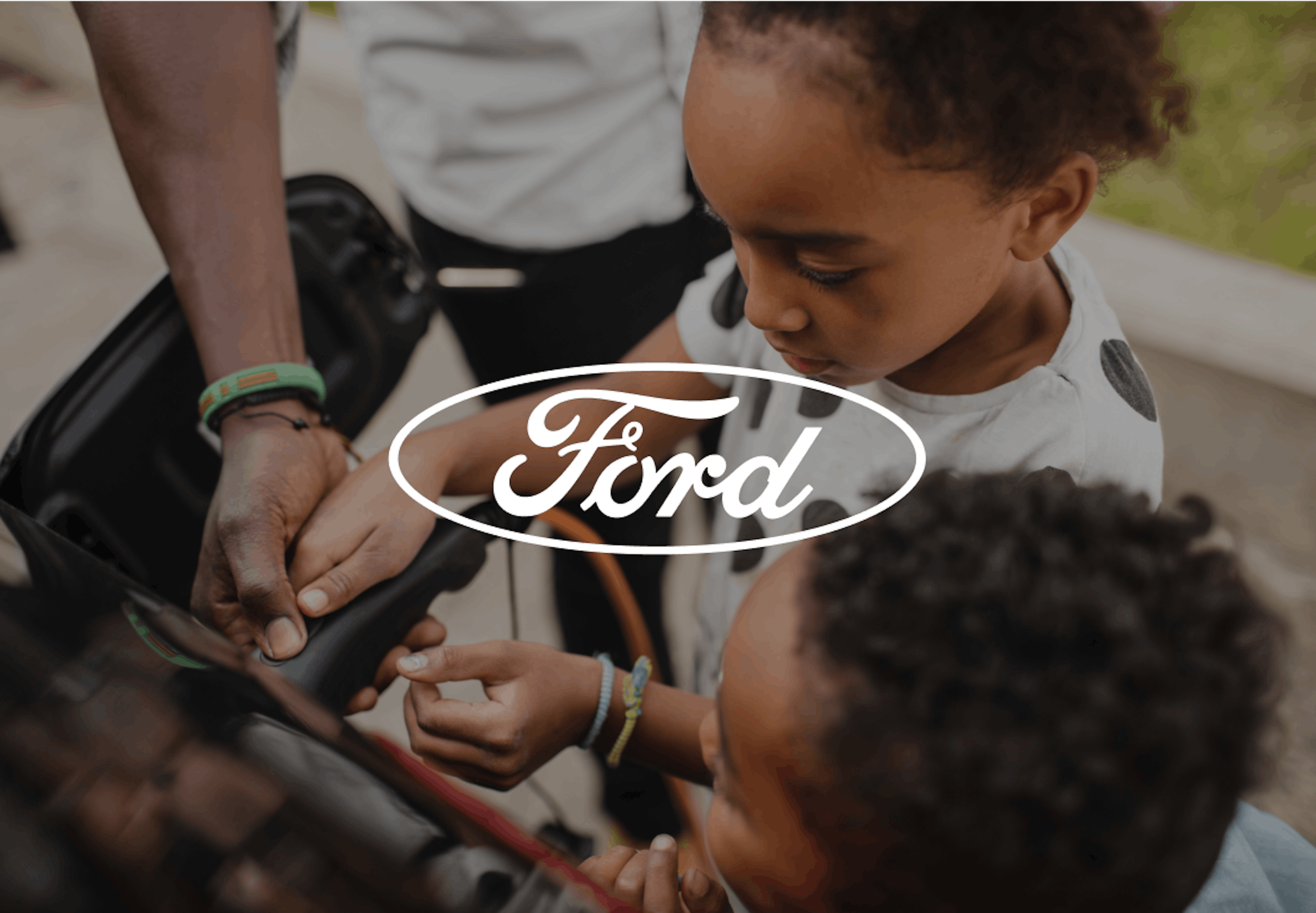 Close-up of children helping an adult charge an electric vehicle, Ford logo overlaid