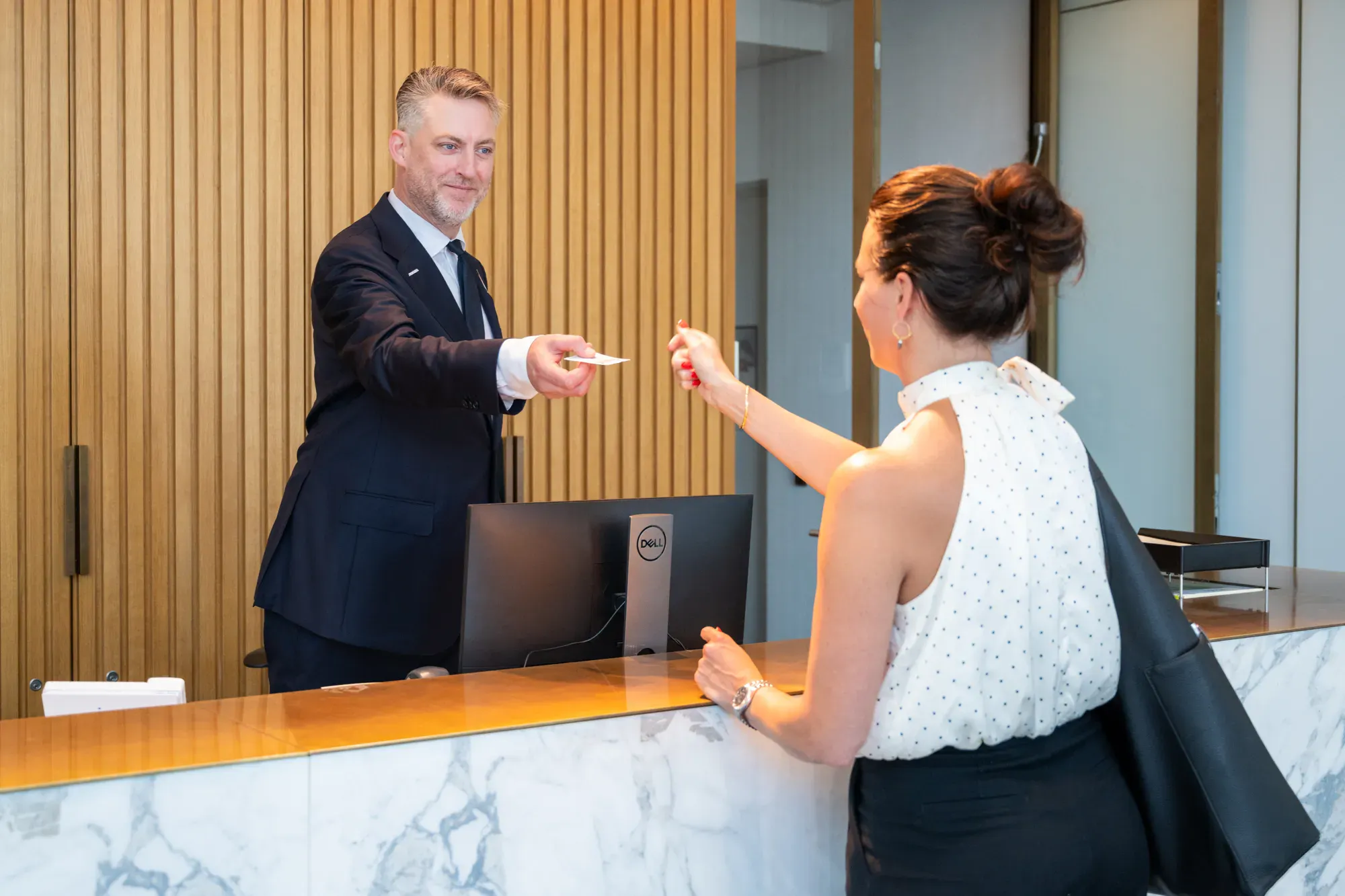 Man achter balie geeft papier aan vrouw
