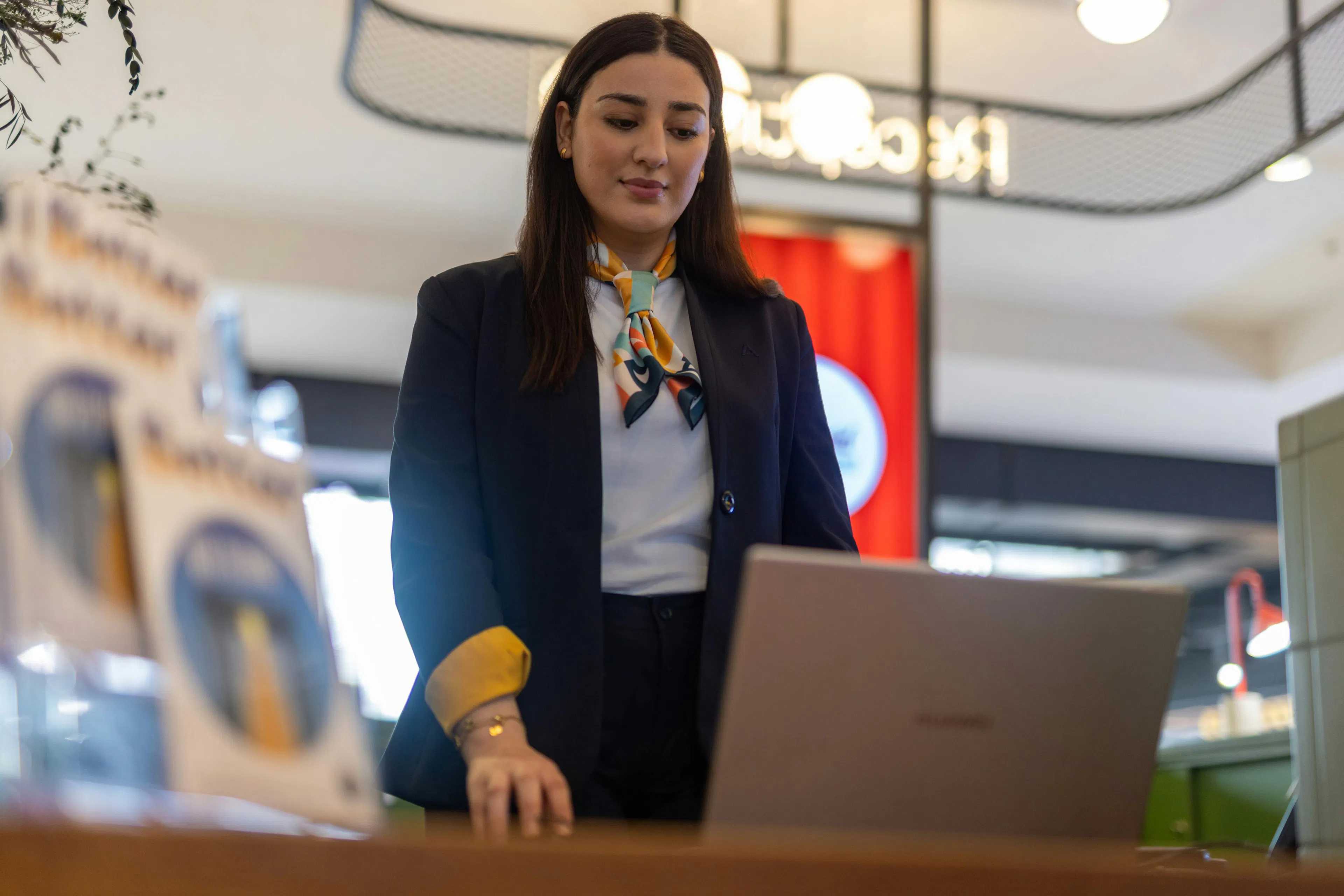 A hostess at her laptop at the reception desk of a shopping center