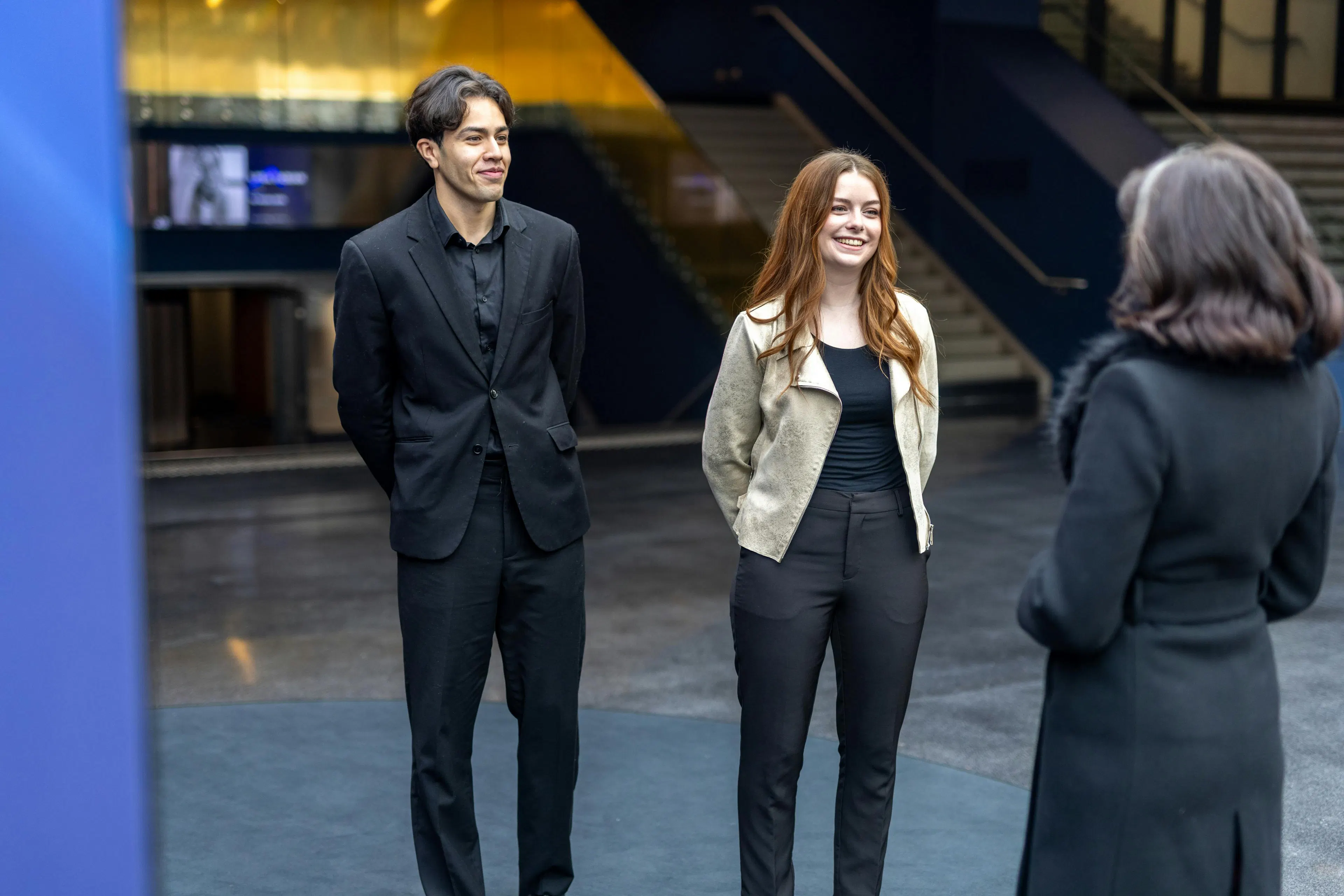 Two hosts welcoming a visitor at an event venue