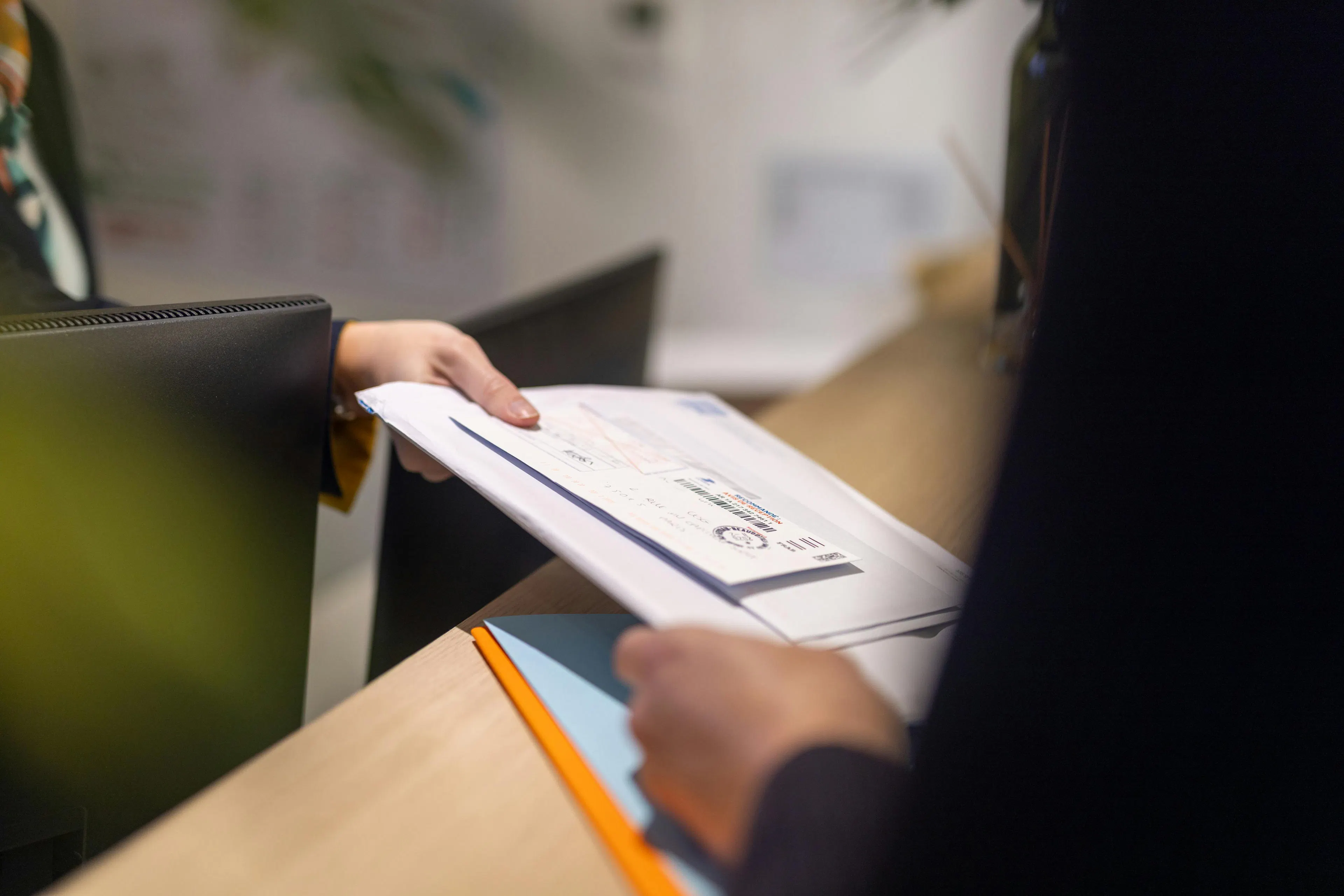 A receptionist handing mail to a colleague